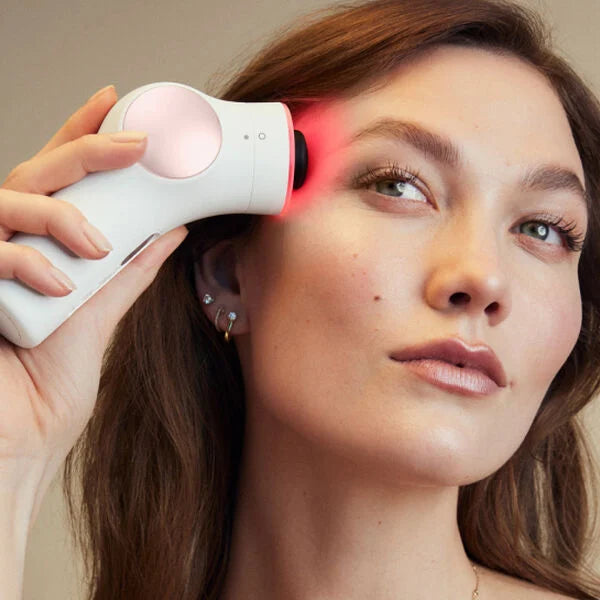 Karlie Kloss white woman using the TheraFace Pro facial massage gun on her face.