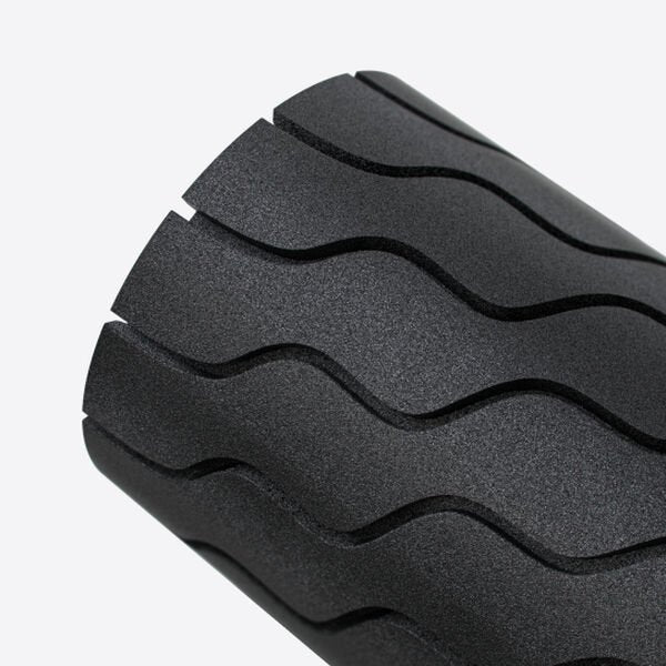 Close up image of a black Theragun Wave Roller vibrating massage foam roller close up wave pattern on white background.